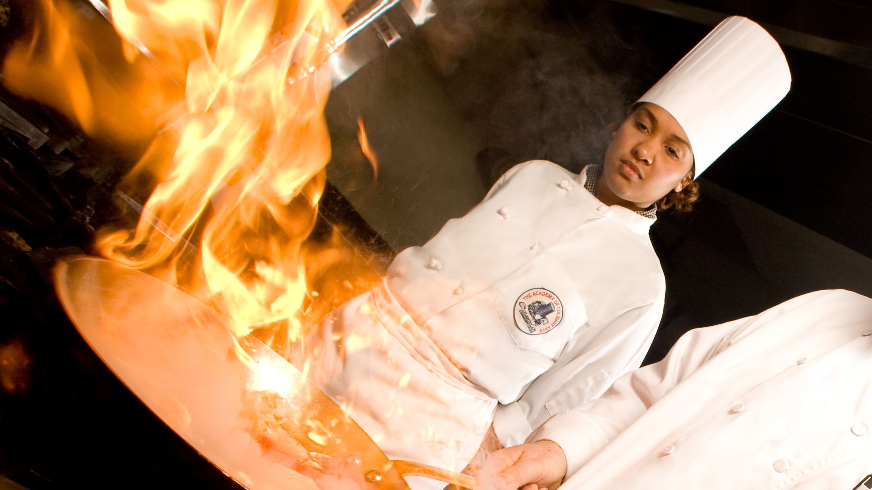 Chef cooking with frying pan as flames ascend