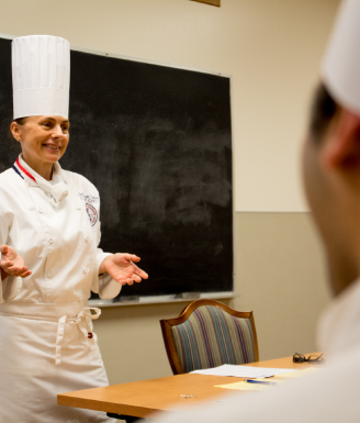chef educator speaking to students in front of a chalkboard