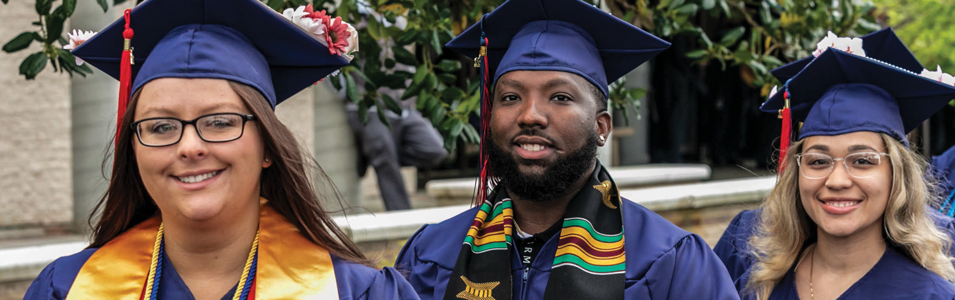 three students in cap and gown