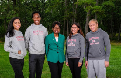 Work study students in matching hoodies smiling with President Gaba
