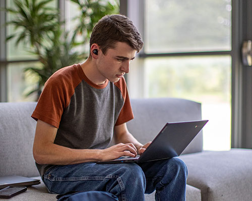 young male student working on a laptop