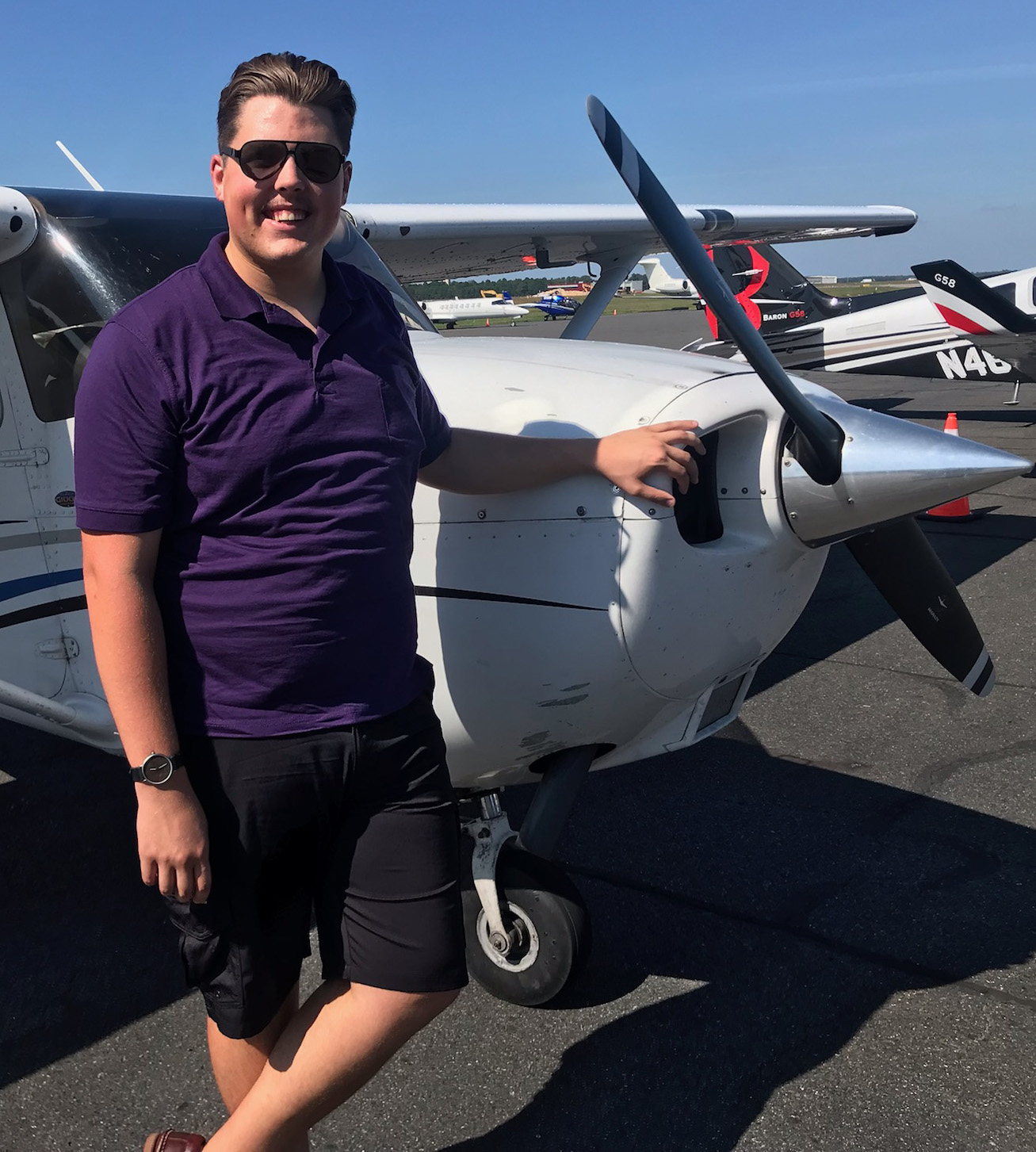 Andrew Rock standing in front of a single engine prop airplane.