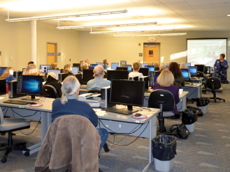 group of adults in computer lab at library, with instructor at front