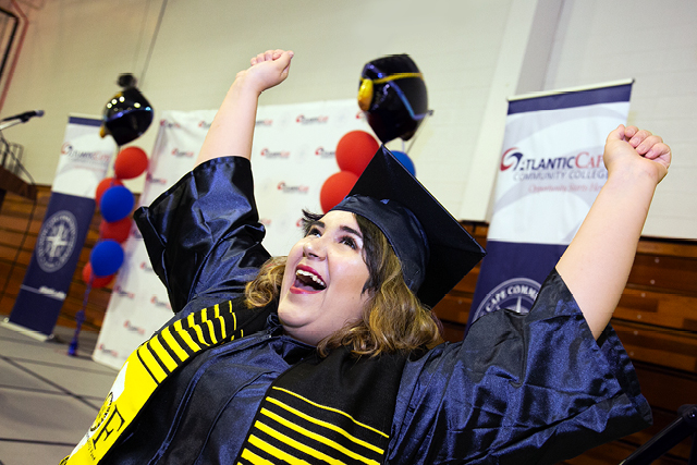  Student in cap and gown raising handing in celebration