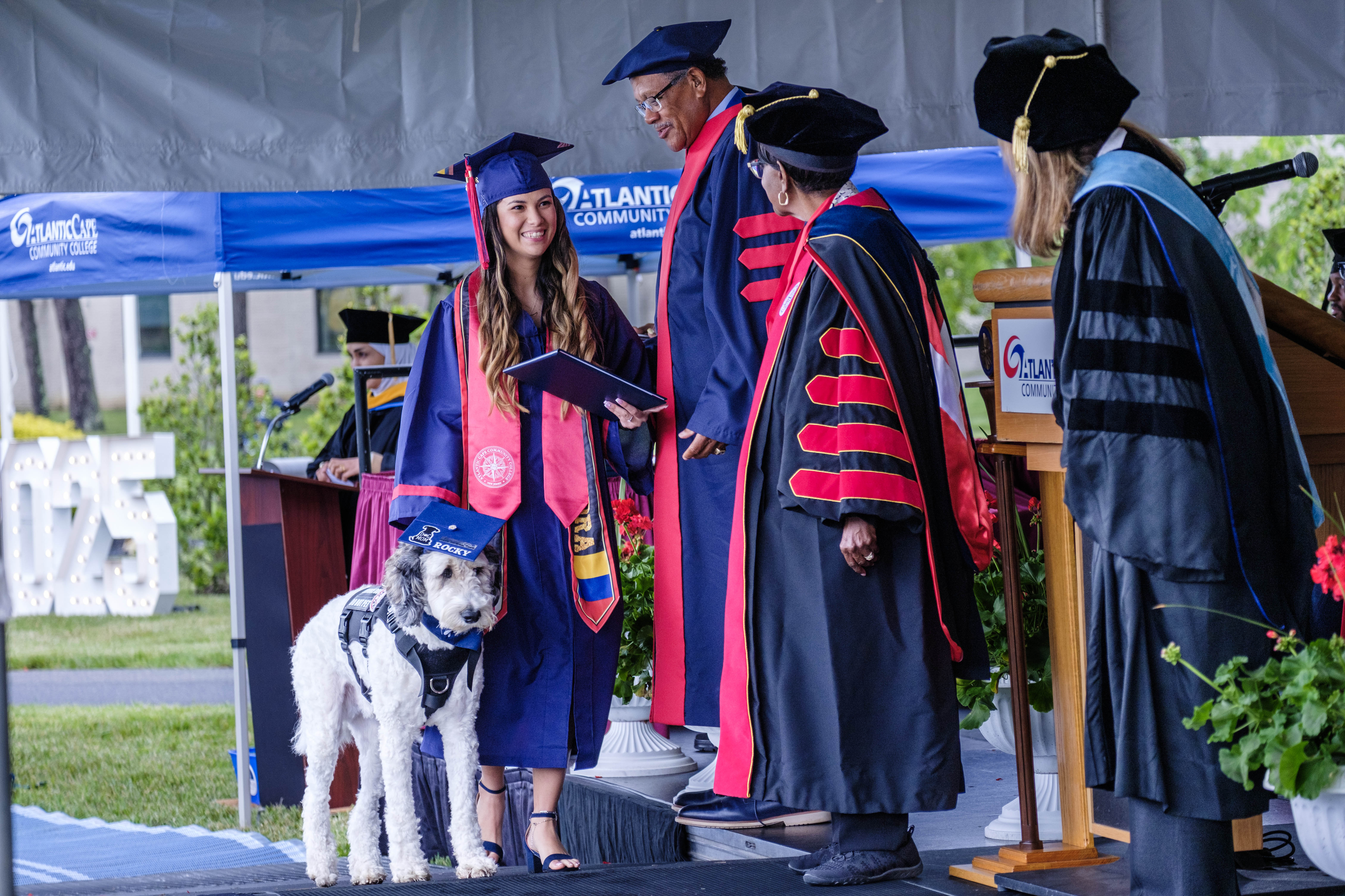 Graduate Alejandra Ceballos and her service dog, Rocky, receive her associate degree