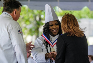 A graduate smiles while receiving her diploma during the culinary arts graduation ceremony on May 17
