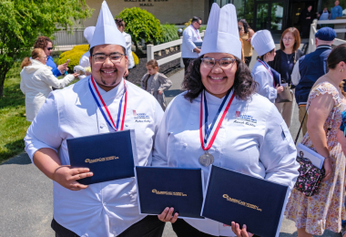 Two culinary arts graduates pose with their diplomas