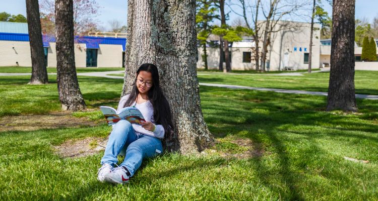Atlantic Cape student enjoys the warm weather reading under a tree